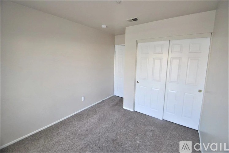 A room with a carpeted floor and two white doors.