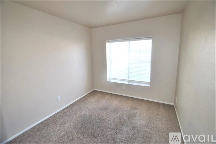 A room with a carpeted floor and a window with blinds.