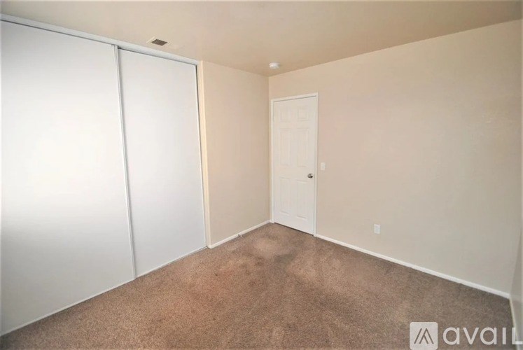 A room with a carpeted floor and a white door.