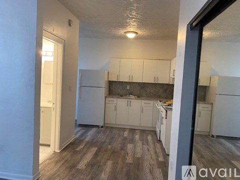 A kitchen with white cabinets and a wooden floor.