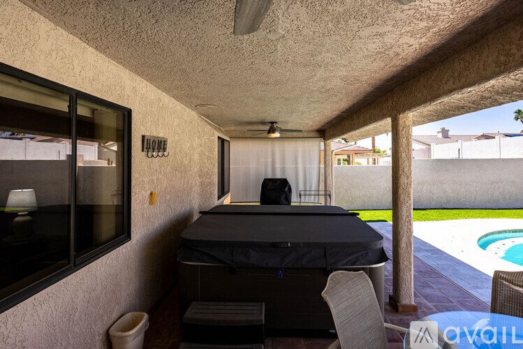 A patio with a table and chairs overlooking a pool.