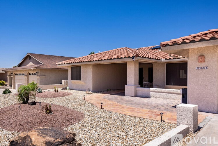 A house with a red tile roof and a gravel garden in front.