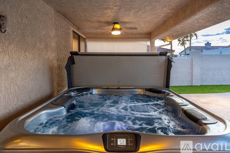 A hot tub with a control panel is in the foreground with a wall and a window in the background.
