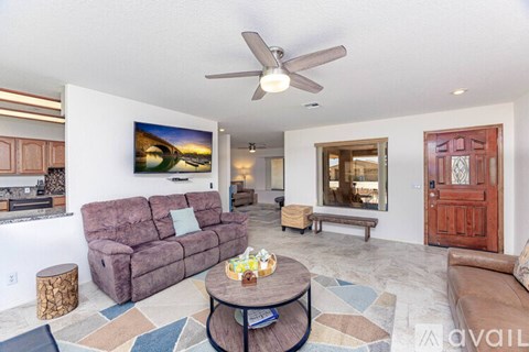 A living room with a purple couch and a painting on the wall.