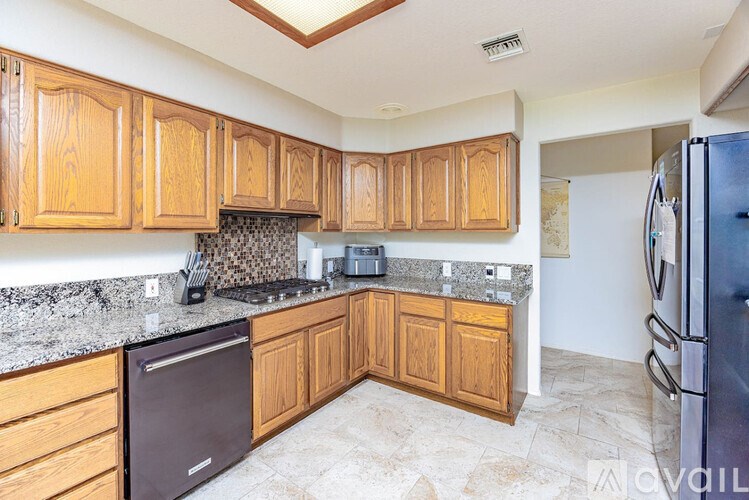 A kitchen with wooden cabinets and a black refrigerator.