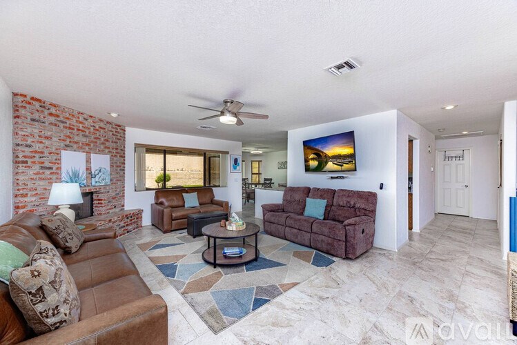 A living room with a brown leather couch and a stone floor.