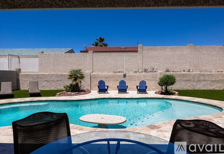 A pool with a table and chairs in front of a wall.