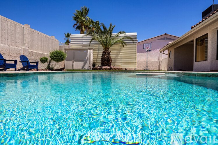 A pool with a palm tree and a basketball hoop in the background.