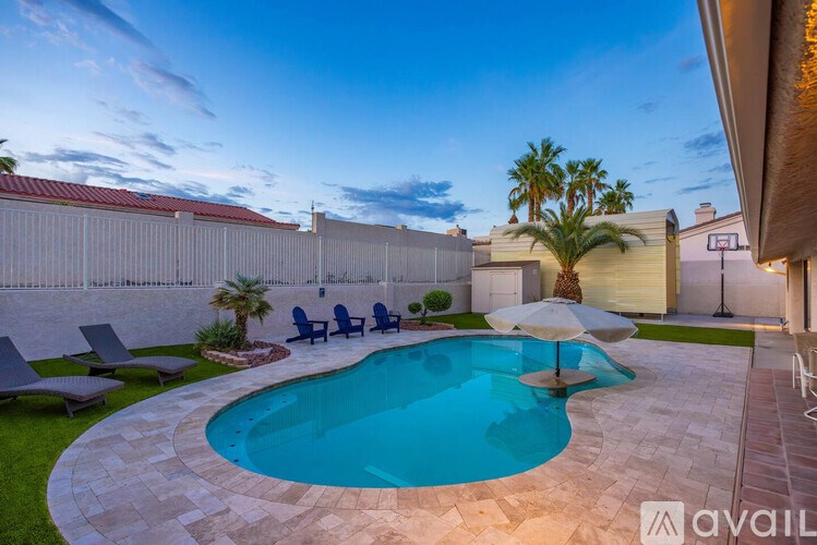 A swimming pool surrounded by a stone patio and lounge chairs.
