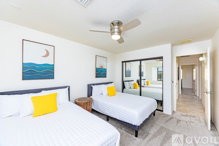 A bedroom with two beds and a ceiling fan.