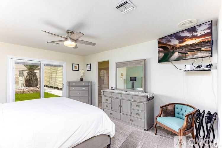 A bedroom with a bed, dresser, chair, and a painting on the wall.