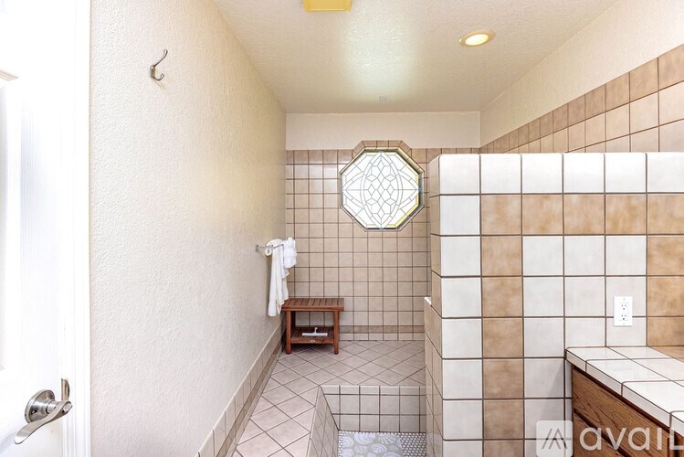 A bathroom with a hexagonal mirror and a bench.