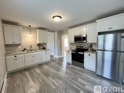 A kitchen with white cabinets and a wooden floor.