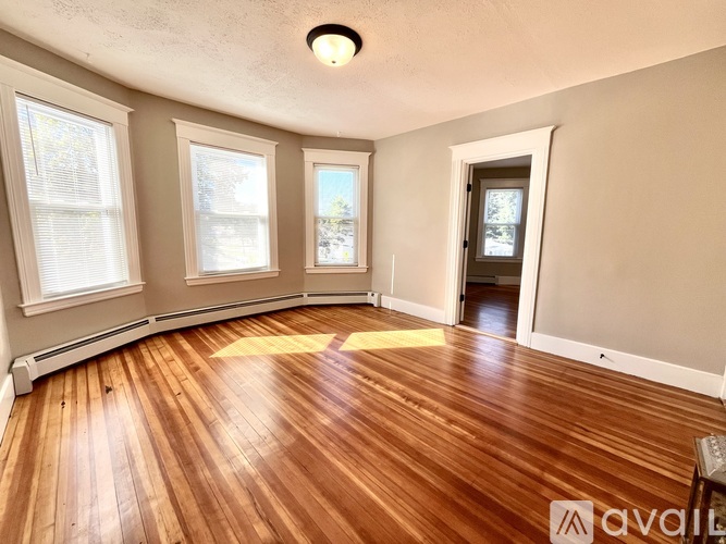 A room with wooden floors and three windows.