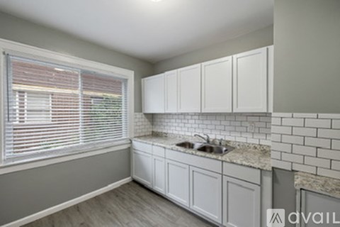 A kitchen with white cabinets and a granite countertop.