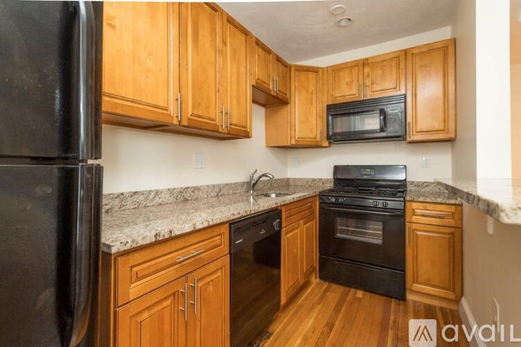 A kitchen with wooden cabinets and black appliances.