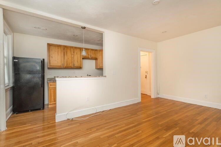 A kitchen with wooden cabinets and a black fridge is available.