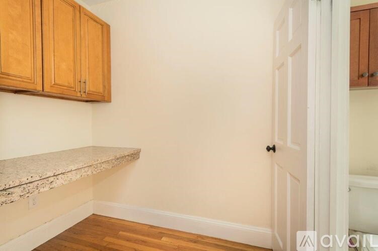 A room with a white door, wooden cabinets, and a marble ledge.