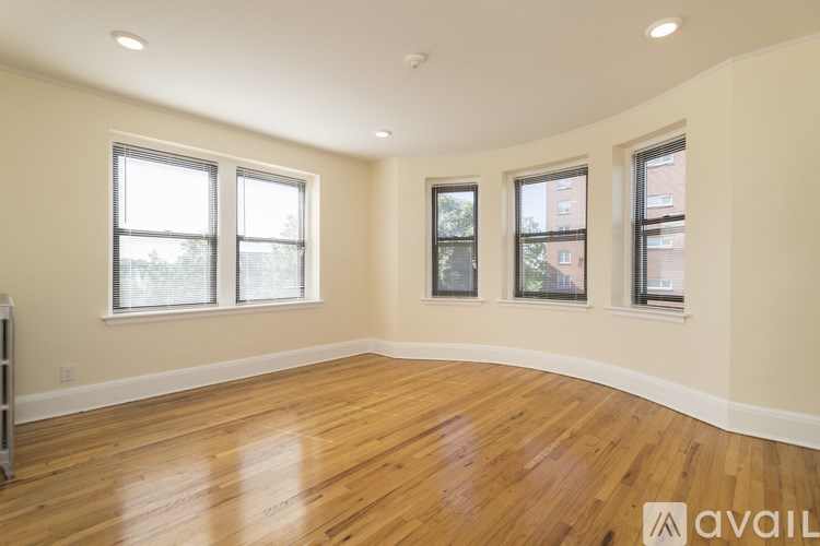 A room with wooden floors and three windows.