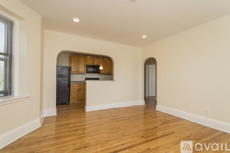 A spacious kitchen with wooden floors and a black refrigerator.
