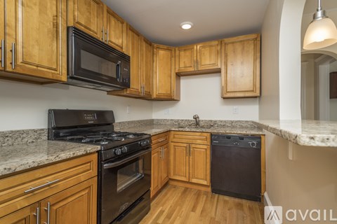 A kitchen with wooden cabinets and black appliances.