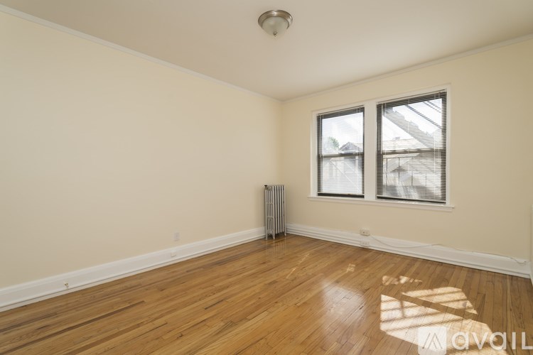 A room with wooden floors and a window with a view of a building outside.