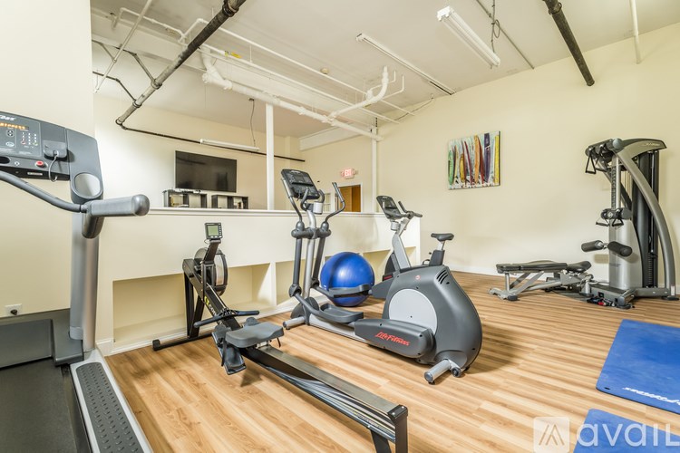 A gym with a variety of exercise equipment including a treadmill, rowing machine, and weight machines.