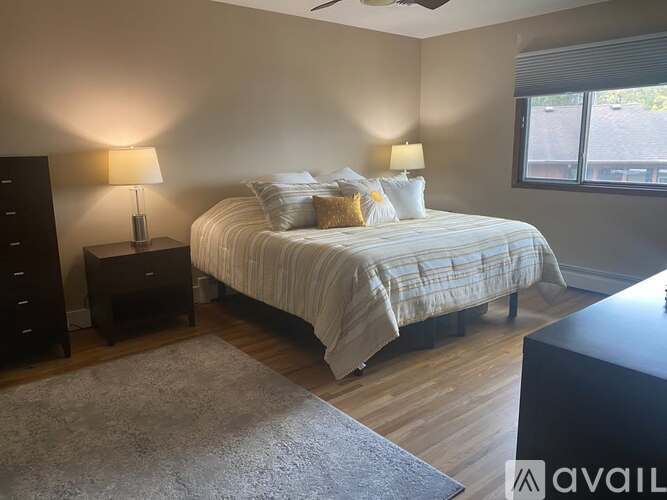 A bedroom with a bed, two lamps, and a dresser.