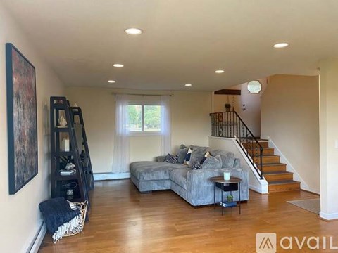 A living room with a grey couch and a staircase.