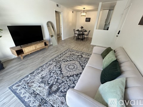 A living room with a white couch and a rug in the center.