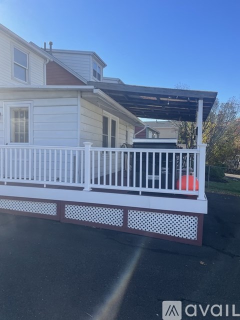 A white house with a red ball on the porch.