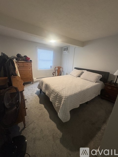 A bedroom with a bed, dresser, and window.