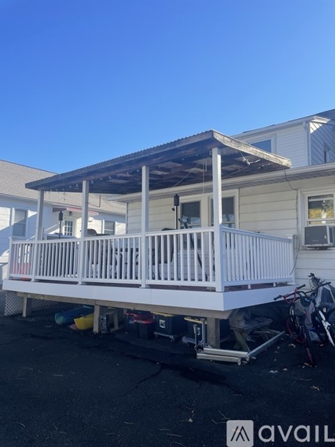 A white deck with a black roof is in front of a house.