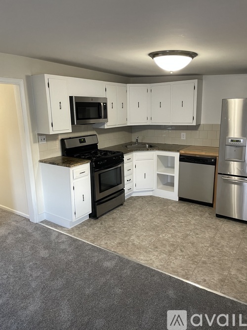 A kitchen with white cabinets and a stainless steel refrigerator.