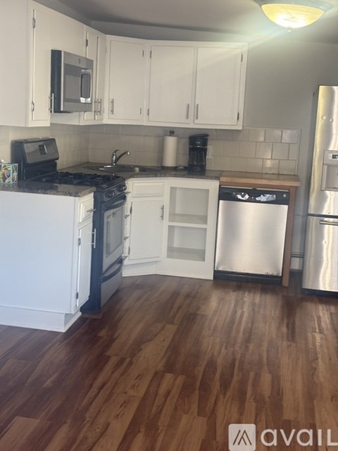 A kitchen with white cabinets and a stainless steel refrigerator.