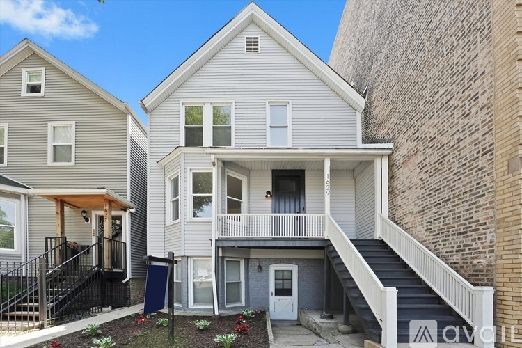 A two-story house with a balcony and stairs leading to the front door.