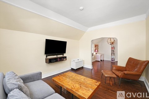 A living room with a grey couch, a wooden coffee table, and a television mounted on the wall.