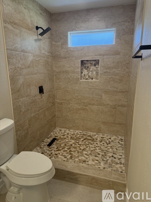 A bathroom with a toilet, tiled walls and a window.