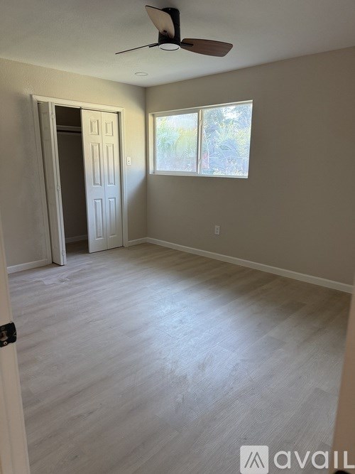A room with a ceiling fan and a door leading to another room.
