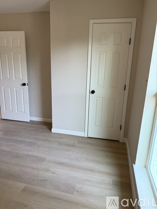 A room with two white doors and a wooden floor.