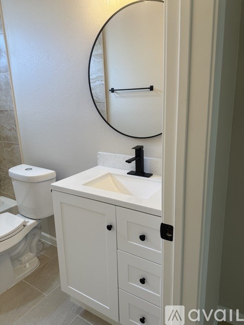 A white bathroom with a toilet, sink and mirror.