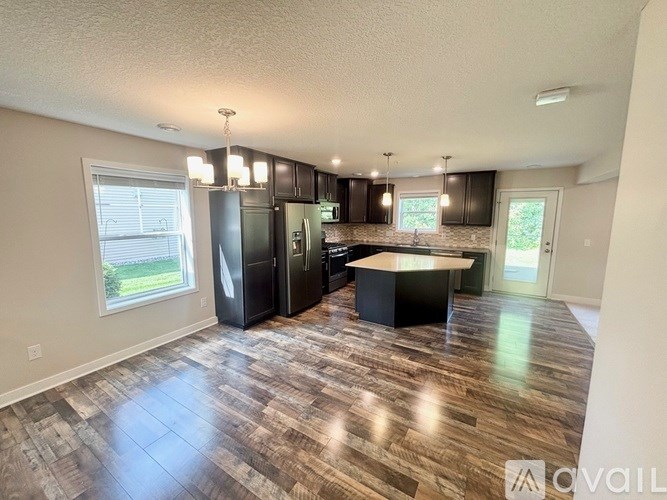 A kitchen with wood flooring and a black island.