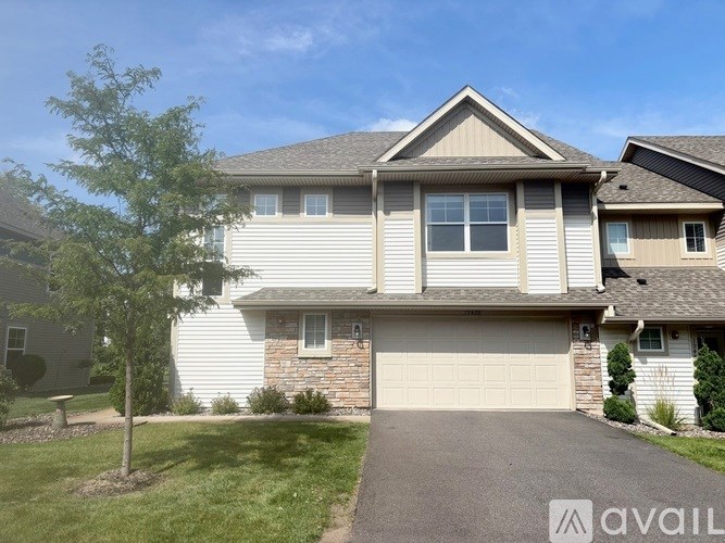 A house with a garage and a tree in front.