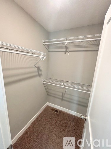 A walk-in closet with shelves and a carpeted floor.