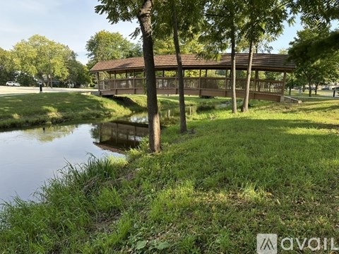 A gazebo sits in the middle of a grassy area next to a body of water.