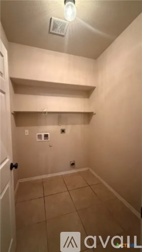 A small, empty room with a tiled floor and a ceiling light.