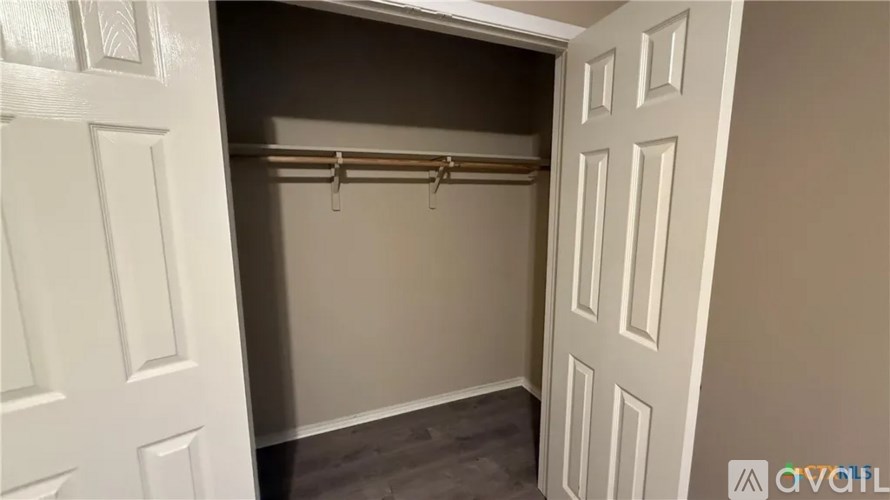 A white door is open to reveal a small closet with a coat hanger.