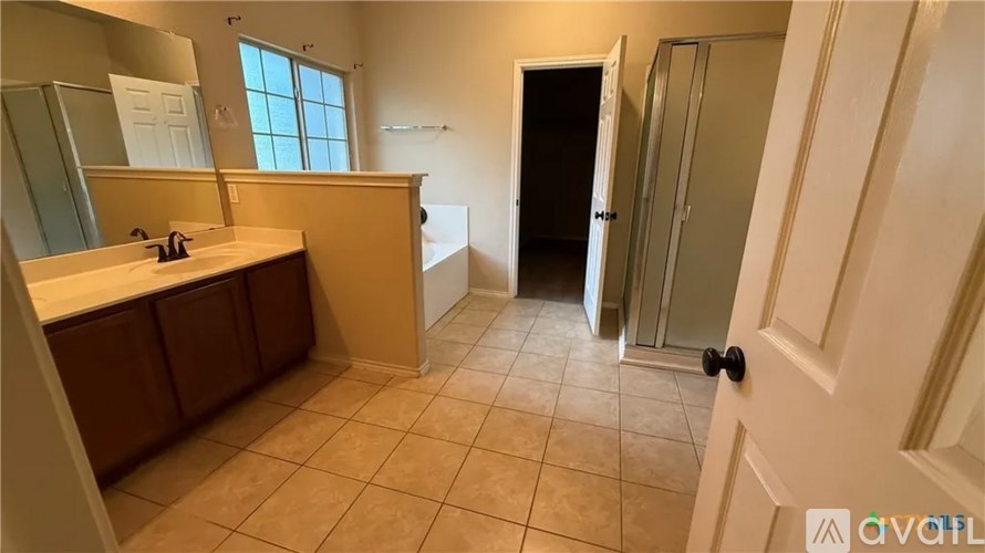 A bathroom with a sink, mirror, and a shower stall.