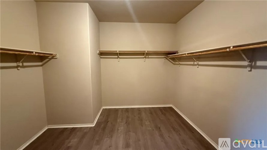 A room with wooden floors and white walls has two sets of clothes racks.