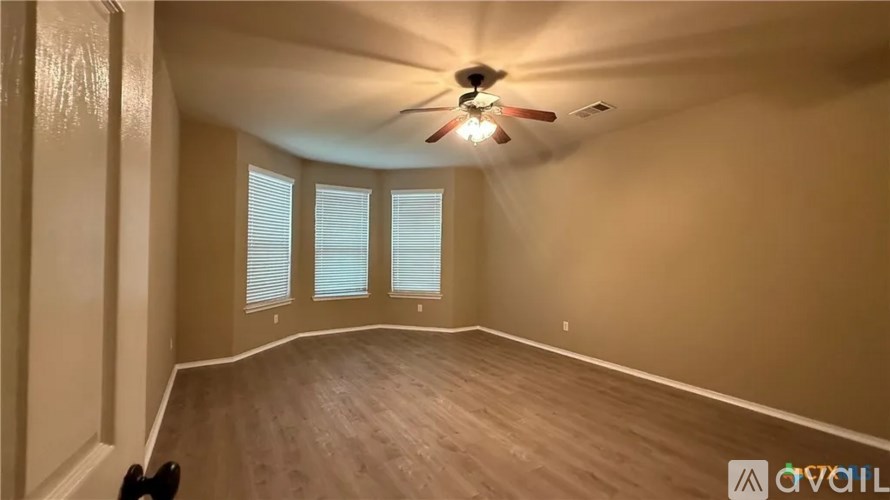 A room with a ceiling fan and wooden flooring.
